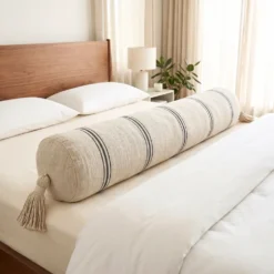 Extra long cream and black striped bolster pillow across a bed