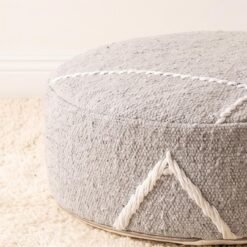 Close-up of light grey geometric cotton pouf showing woven texture and raised decorative lines