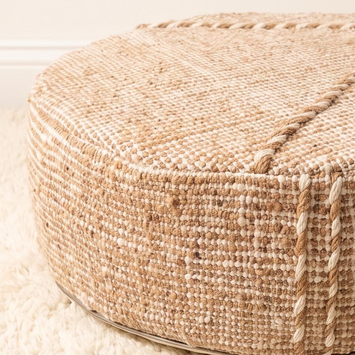 Close-up of natural beige cotton pouf showing textured weave and raised seam