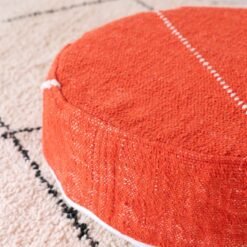 Close-up of orange cotton pouf with ivory stitched geometric lines