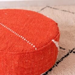 Angled close-up of orange cotton pouf with a fine ivory stitched line